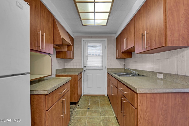 kitchen with white fridge, custom range hood, ornamental molding, and sink