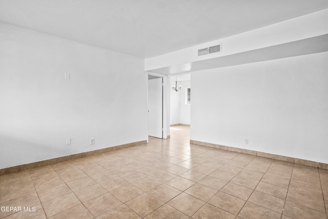 tiled empty room with an inviting chandelier