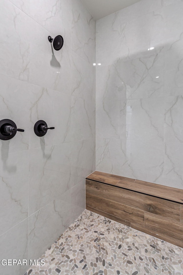 full bathroom with stone finish flooring and a tile shower