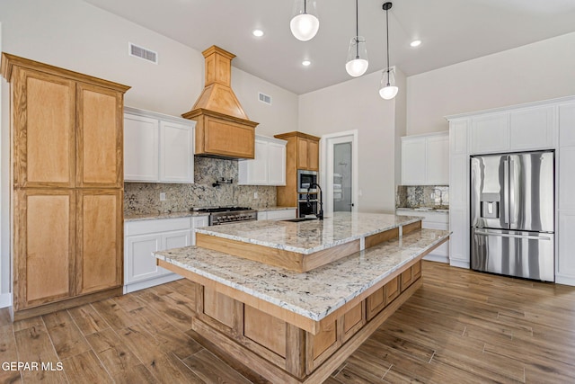 kitchen with stainless steel appliances, visible vents, and wood finished floors