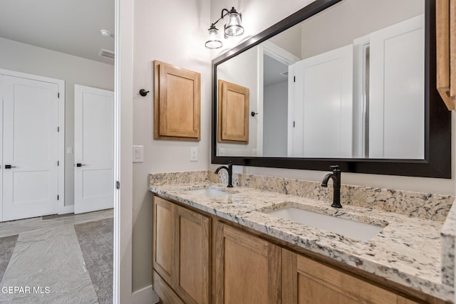 bathroom featuring double vanity, baseboards, and a sink