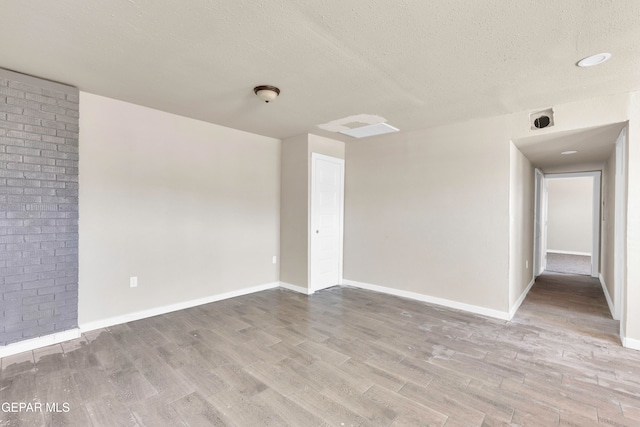 spare room featuring a textured ceiling and light hardwood / wood-style flooring