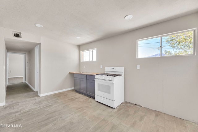 kitchen featuring light hardwood / wood-style floors, a textured ceiling, white gas stove, and gray cabinets