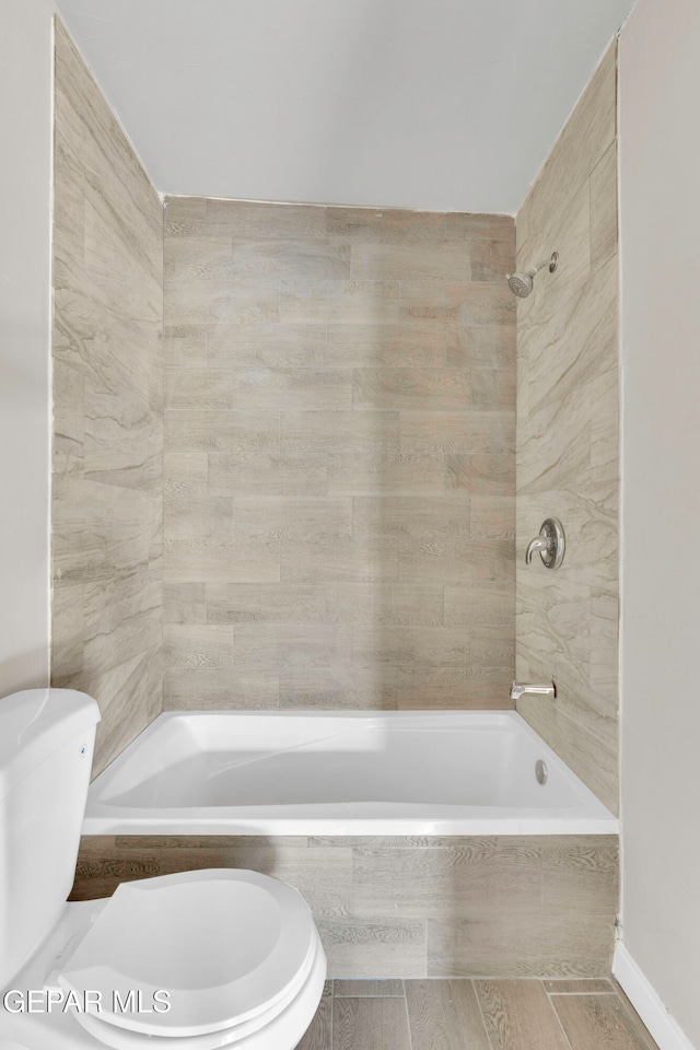 bathroom featuring tiled shower / bath combo and toilet