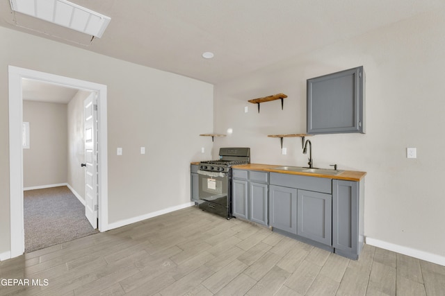 kitchen featuring black gas range, sink, gray cabinetry, and wood counters