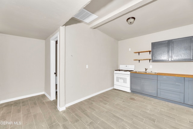 kitchen with beamed ceiling, white gas stove, sink, light wood-type flooring, and gray cabinets