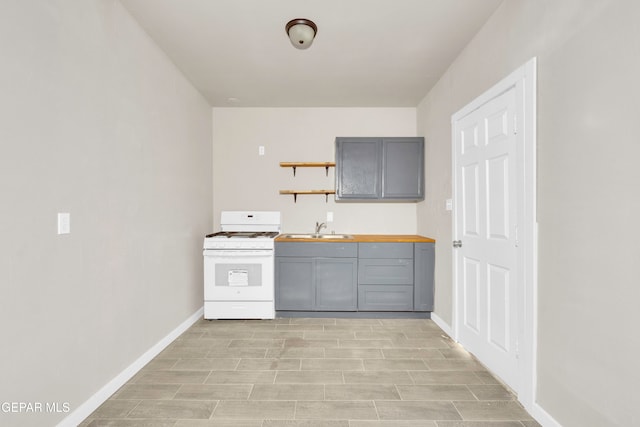 kitchen with gray cabinetry, white gas stove, sink, and wooden counters