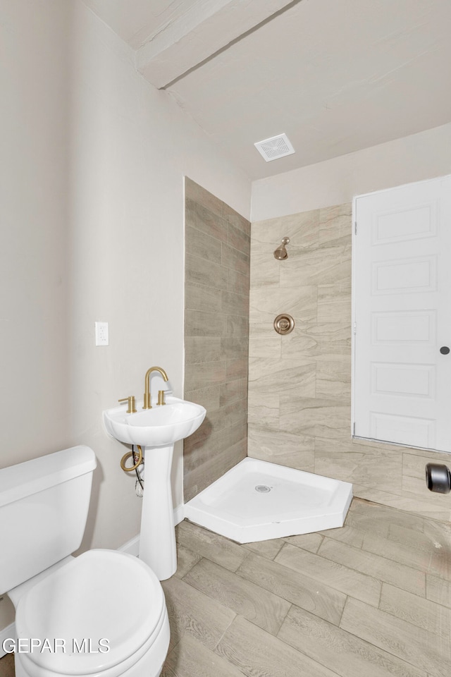 bathroom with tiled shower and toilet