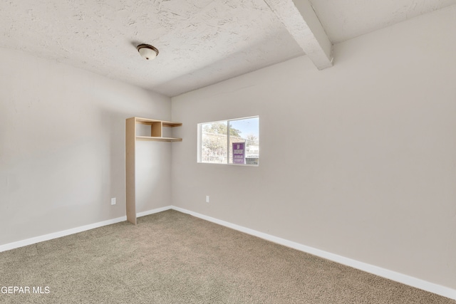 carpeted spare room featuring a textured ceiling and beam ceiling