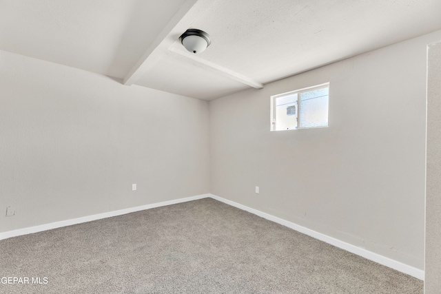 carpeted empty room featuring beamed ceiling