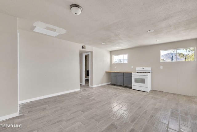 kitchen with a textured ceiling, gray cabinetry, light wood-type flooring, and gas range gas stove