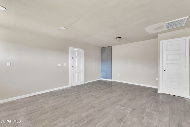 spare room with a textured ceiling and light wood-type flooring