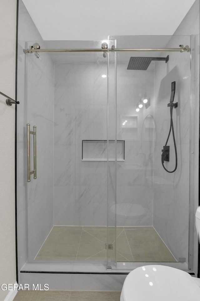 bathroom with a shower with shower door and toilet