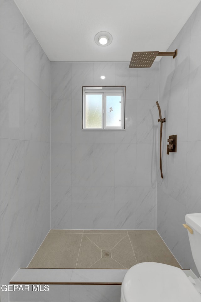 bathroom featuring a tile shower and toilet