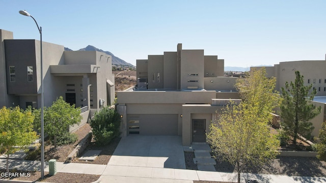 pueblo-style house with a garage and a mountain view