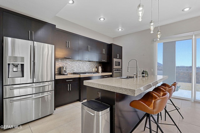 kitchen featuring a center island with sink, a breakfast bar area, sink, pendant lighting, and stainless steel appliances