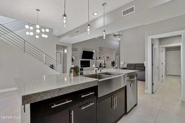 kitchen featuring hanging light fixtures, a center island with sink, sink, light tile patterned floors, and stainless steel dishwasher