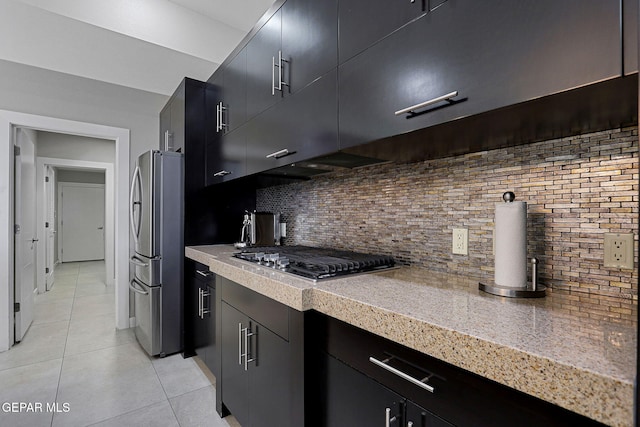 kitchen with appliances with stainless steel finishes, tasteful backsplash, and light tile patterned floors