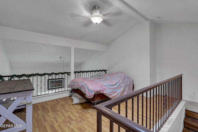 bedroom with vaulted ceiling with beams, hardwood / wood-style floors, a textured ceiling, and ceiling fan