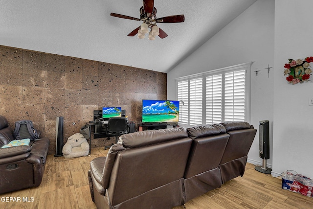 living room with ceiling fan, a textured ceiling, tile walls, vaulted ceiling, and light hardwood / wood-style flooring