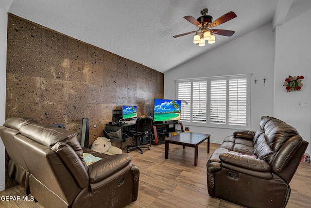 living room with a textured ceiling, light hardwood / wood-style floors, ceiling fan, tile walls, and vaulted ceiling