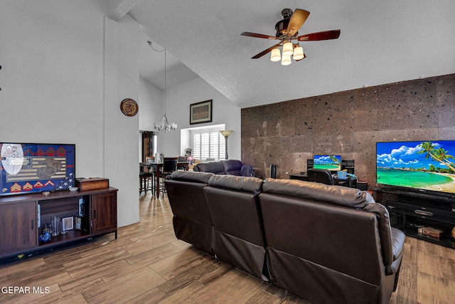 living room featuring hardwood / wood-style floors, a textured ceiling, high vaulted ceiling, tile walls, and ceiling fan with notable chandelier