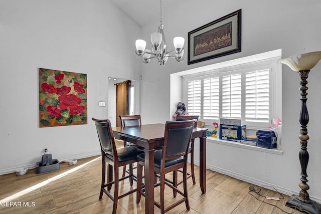 dining area with a towering ceiling, a notable chandelier, and light wood-type flooring