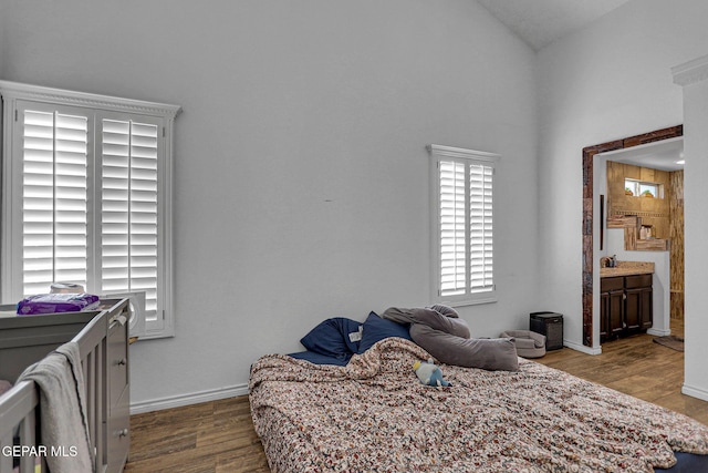 bedroom with connected bathroom, hardwood / wood-style flooring, and vaulted ceiling