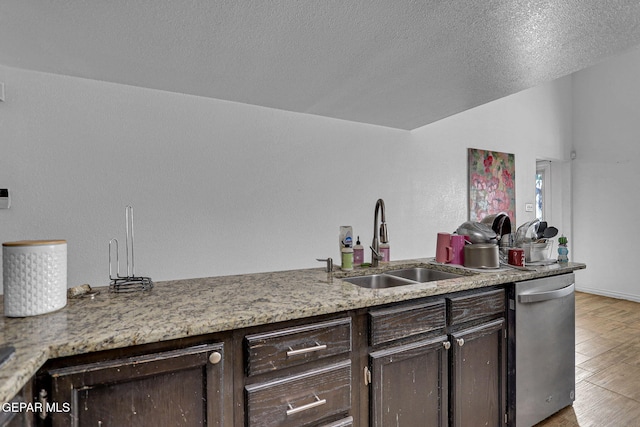 kitchen featuring sink, light wood-type flooring, a textured ceiling, dark brown cabinetry, and stainless steel dishwasher