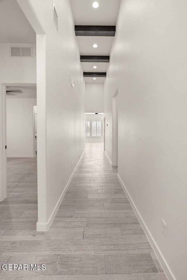 hallway with beamed ceiling and light wood-type flooring