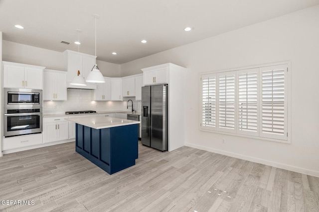 13397 Highworth Dr, El Paso, TX 79928 - kitchen with appliances with stainless steel finishes, a center island, light countertops, white cabinets, and light wood-style flooring