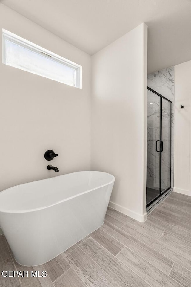 13397 Highworth Dr, El Paso, TX 79928 - full bathroom with baseboards, a marble finish shower, a freestanding bath, and wood finished floors