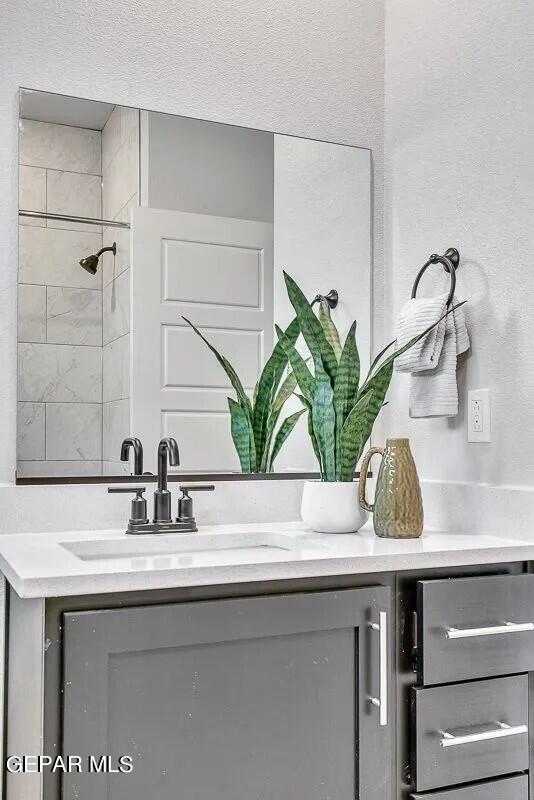 bathroom with vanity and a tile shower