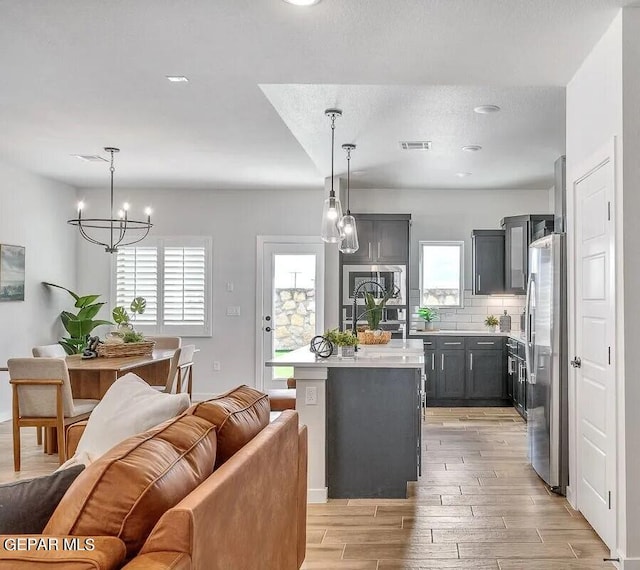 kitchen featuring backsplash, a chandelier, pendant lighting, light hardwood / wood-style floors, and a center island