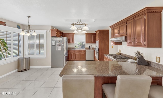 kitchen featuring kitchen peninsula, hanging light fixtures, a breakfast bar, light stone countertops, and stainless steel appliances