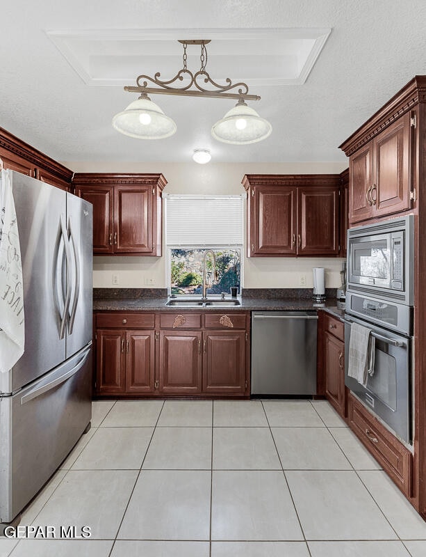 kitchen with sink, appliances with stainless steel finishes, hanging light fixtures, and light tile patterned flooring