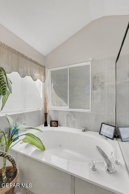 bathroom featuring vaulted ceiling and a bath