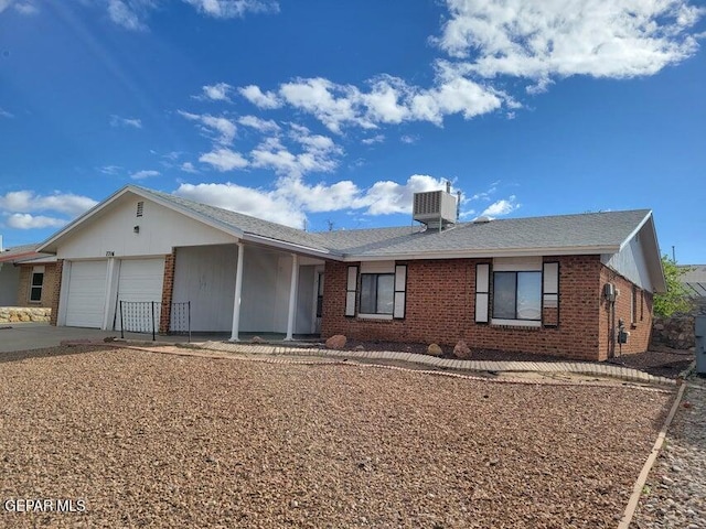 single story home with cooling unit and a garage