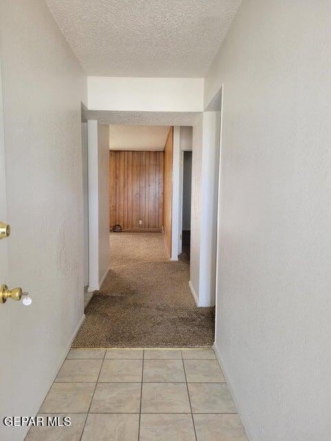 hall featuring light carpet and a textured ceiling