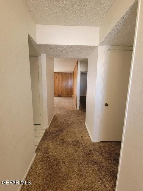 corridor with a textured ceiling and light colored carpet