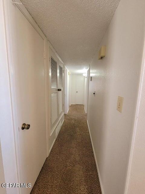 corridor featuring a textured ceiling and carpet floors