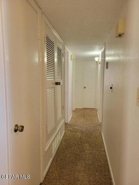 hallway featuring carpet flooring and a textured ceiling