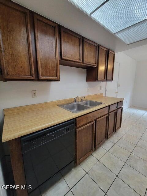 kitchen with black dishwasher, dark brown cabinetry, sink, and light tile patterned floors