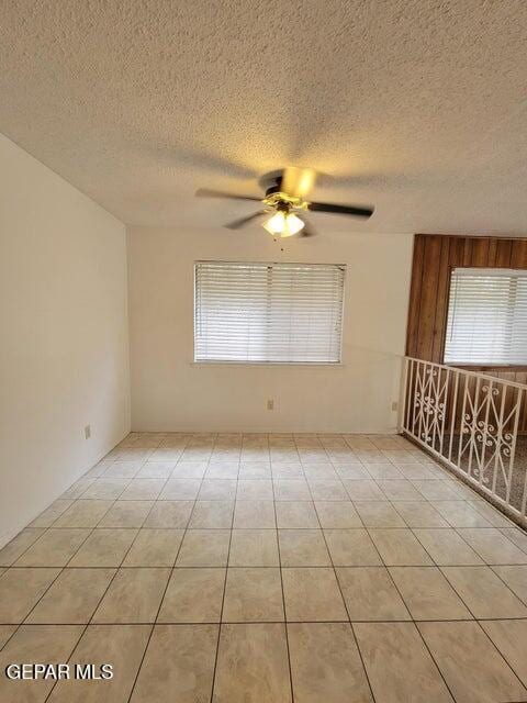 spare room with ceiling fan, a textured ceiling, and light tile patterned flooring