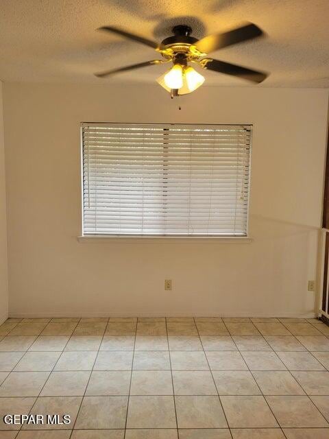 unfurnished room featuring a textured ceiling, light tile patterned floors, and ceiling fan