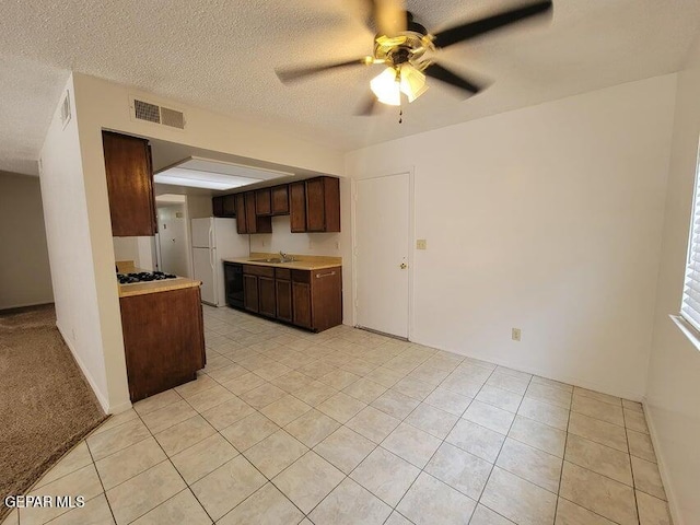 kitchen featuring sink, light tile patterned floors, a textured ceiling, white appliances, and ceiling fan