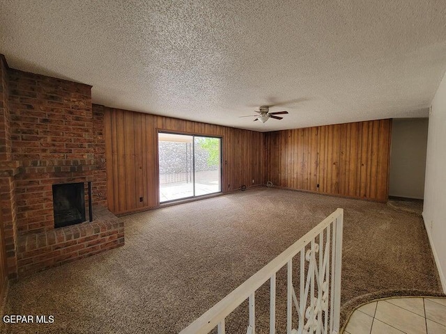 unfurnished living room with light colored carpet, wood walls, a textured ceiling, and ceiling fan