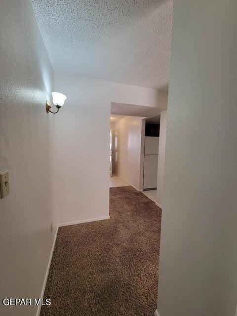 hall featuring a textured ceiling and light colored carpet