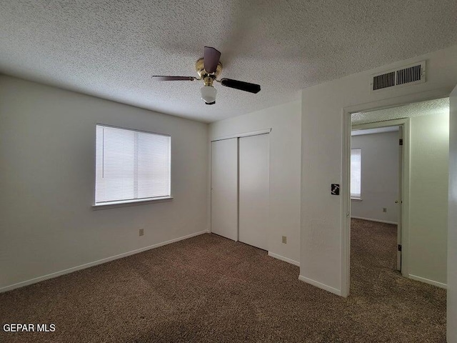 unfurnished bedroom with a closet, ceiling fan, multiple windows, and dark colored carpet