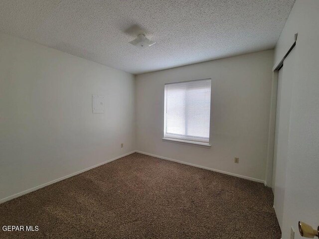 carpeted empty room featuring a textured ceiling